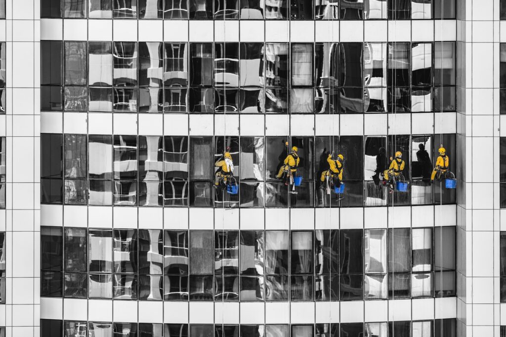 window cleaners abseiling down glass building